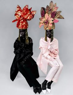 two black women wearing head coverings sitting next to each other on a white surface