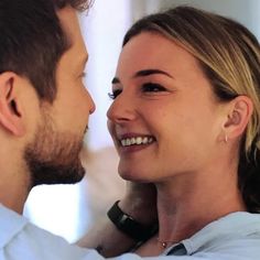 a man and woman smile at each other while they are looking into each other's eyes