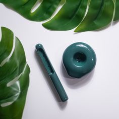 a green donut next to a pen on top of a leafy tablecloth