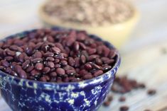 two bowls filled with red beans on top of a wooden table