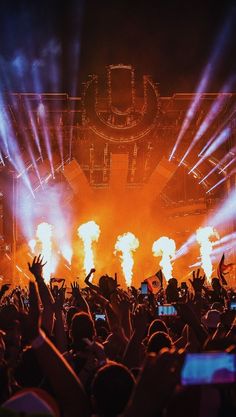 a crowd at a concert with their hands up in the air and lights on behind them