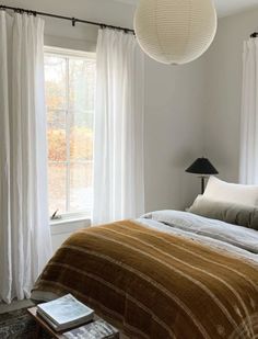 a bed sitting under a window next to a lamp