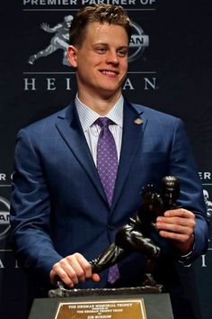 a man in a suit and tie holding a trophy