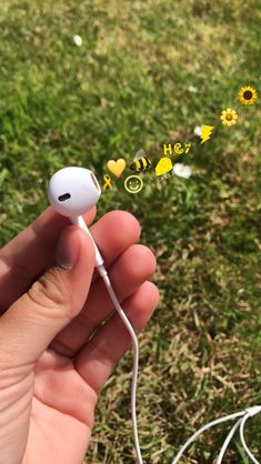 someone is holding an earphone in their hand with flowers and hearts floating out of it