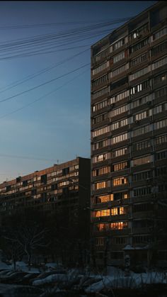 an apartment building is lit up at night in the winter with snow on the ground