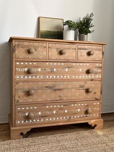 a wooden dresser with many drawers and knobs on it's sides, in front of a white wall