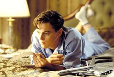 a young man laying on top of a bed next to a lamp and remote control