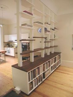 a living room filled with lots of furniture and bookshelves on top of wooden floors