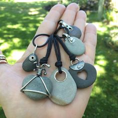 a person holding some rocks in their palm with charms attached to the clasps on them