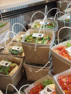 plastic containers filled with salads and vegetables on top of a counter in a restaurant