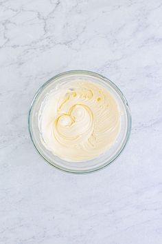 a glass bowl filled with cream on top of a white counter