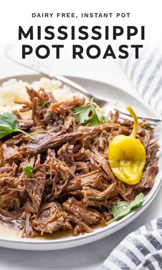 a white plate topped with shredded meat and garnished with parsley next to mashed potatoes