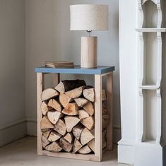 a stack of firewood sitting on top of a blue table next to a lamp