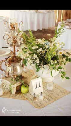 an arrangement of flowers, candles and teapots on a table with napkins