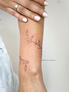 a woman's arm with a flower tattoo on the left side of her arm