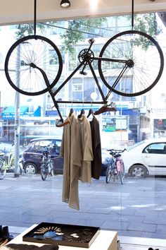 a bicycle hanging on a clothes rack in front of a window with cars parked outside