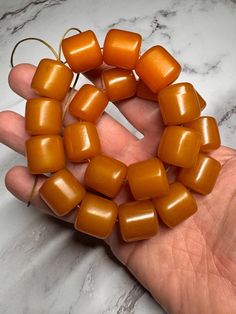 a hand is holding several small orange beads