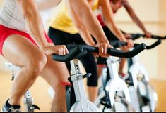 three people riding stationary bikes in a gym