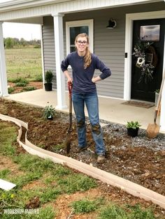 a woman standing in front of a house holding a shovel