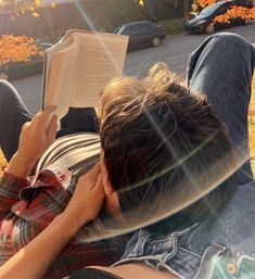 a person laying down reading a book in the grass with their head on his hands