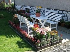 a white bench sitting next to a garden filled with flowers