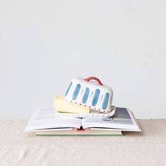 an open book sitting on top of a wooden table next to a white and blue cake