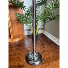 a lamp that is on top of a wooden floor next to a potted plant