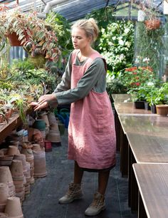 a woman in an apron is looking at potted plants