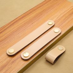 two pieces of leather sitting on top of a wooden table