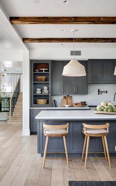 a kitchen with two stools in front of an island