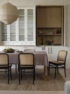 a dining room table with four chairs and a light hanging over it