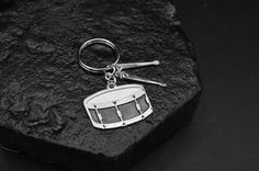 a metal keychain with a drum on it sitting on a rock next to a pair of scissors