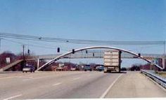 an overpass on the side of a highway with power lines above it and cars driving down the road