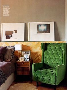 a green chair sitting in front of a bed next to two pictures on the wall