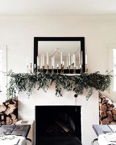 the fireplace is decorated with greenery and candles