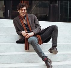 a man sitting on some steps wearing a scarf