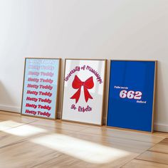 three framed posters on the wall in an empty room with hard wood flooring and white walls