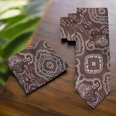 This silk necktie, featuring shades of brown with a detailed paisley pattern, is a refined and versatile accessory that adds a touch of classic charm to any ensemble. The intricate paisley design, rich in texture and depth, showcases a blend of tradition and elegance, making it a standout piece in both professional and social settings. Dress Shirts: Cream Dress Shirt: A cream-colored shirt complements the warm tones of the brown paisley tie, creating a harmonious and sophisticated look. This pai Classic Brown Suit And Tie Accessories As Gift, Dapper Brown Tie For Business, Elegant Paisley Print Tie As A Gift, Elegant Brown Suit And Tie Accessories With Pocket Square, Brown Suit And Tie Accessories With Pocket Square, Dapper Brown Suit And Tie Accessories For Semi-formal Occasions, Classic Brown Pocket Square For Formal Occasions, Elegant Brown Pocket Square For Business, Elegant Paisley Print Ties As Gift