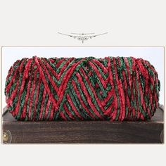 a red and green rope on top of a wooden table next to a white frame