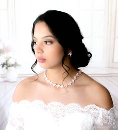 a woman in a white dress wearing a pearl necklace and pearls on her neck, looking off to the side