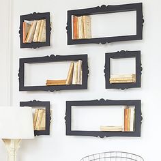 four bookshelves are mounted on the wall above a table with a lamp and chair