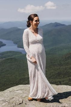 a pregnant woman standing on top of a mountain