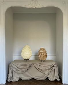 two vases sitting on top of a table covered in a gray cloth next to each other