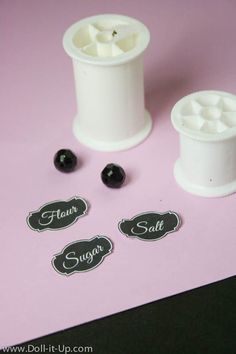 some black and white items are on a pink table top with labels that say sugar