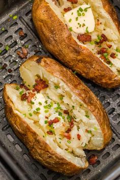 two baked potatoes with cheese and chives on a baking tray in the oven, ready to be cooked