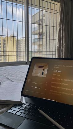 an open laptop computer sitting on top of a desk next to a window with panoramic windows