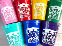 six colorful cups with the words kinder grad on them