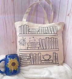 a tote bag sitting on top of a bed next to a coffee mug and bookshelf