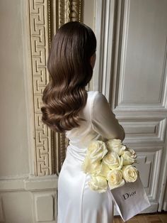 the back of a woman's head holding a bouquet of white roses