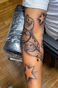 a person with a tattoo on their arm has musical notes and stars around them,